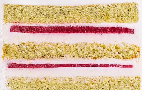 Layers of cake with green sponge and red filling on display in a kitchen Stock Photos
