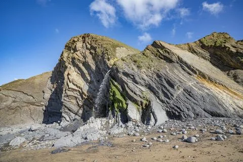 Layers of different colours of rock and waterfall on Sandymouth cliff Cornwal Stock-Fotos