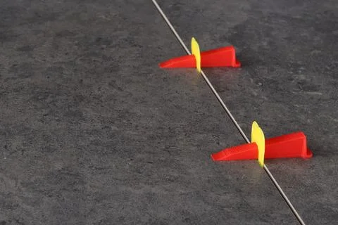 Laying ceramic tiles using leveling spacers. Bright red wedges 写真素材