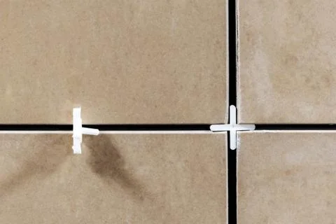 Laying ceramic tiles using plastic crosses. Use plastic crosses to align the  Stock Photos