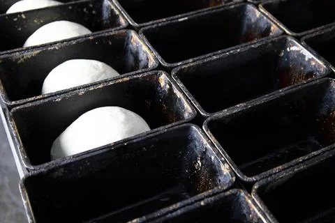 Laying the dough in the molds for future bread. Stock Photos