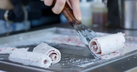 Laying down fresh ice cream rolls on cold stone plate - close up - slow motio Stock Footage 125258950