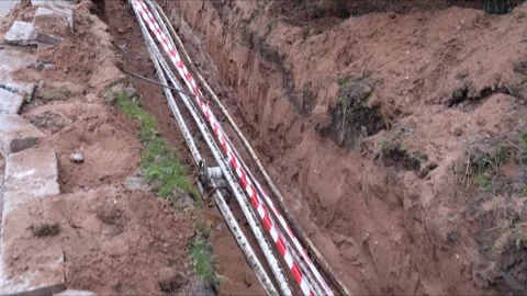 Laying electric cable in a deep trench with exposed underground utilities. Stock Footage 323113844