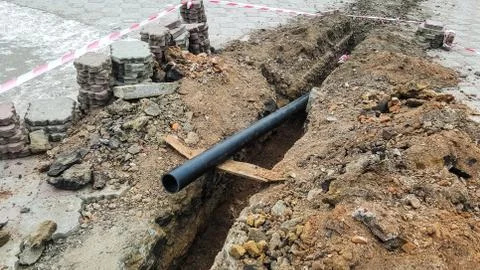 Laying installation of a new cable in a plastic pipe. Digging drilling of the Stock Photos