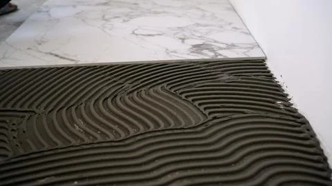Laying marble effect tiles with thin-set mortar on floor Stock Photos