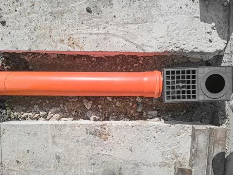Laying an orange plastic drainage pipe with a rain catcher. Top view. Stock Photos