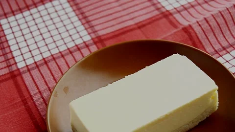 Laying out a brown plate with a rectangular slice of delicious cheesecake 動画素材 302374613