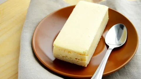 Laying out a brown plate with a rectangular slice of delicious cheesecake c.. Foto stock