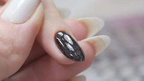 Laying out a pattern of rhinestones on the nail with a spatula and a thin brush. Stock Footage 254904101