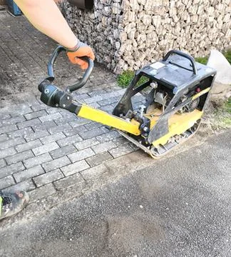 Laying paving slabs using a vibrating plate 스톡 사진