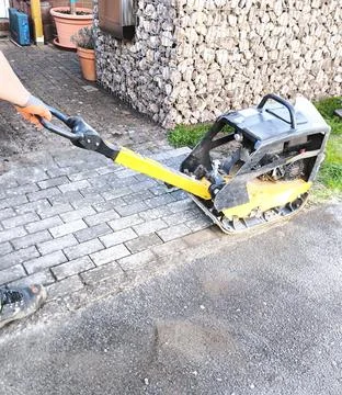 Laying paving slabs using a vibrating plate Stock Photos