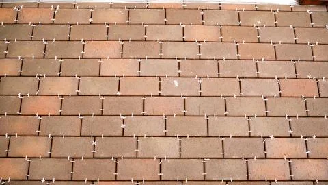 Laying reddish brown clinker tiles in a running bond pattern with white pla.. Stock Photos
