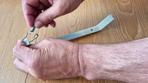 Laying a Tension Spring from a Metal Hook Using Hand Tools Stock Footage 340541029