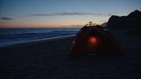 Laying in tent with view of sunset on ocean coast Stock Footage 127409431