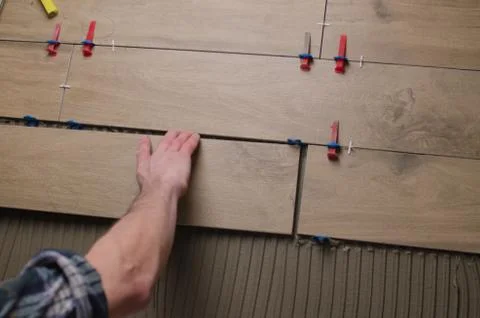 Laying tile on the floor, ceramic tile laying, pressing down and regulating,  Stock Photos