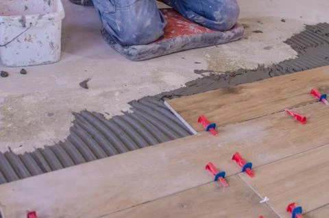 Laying tile on the floor, ceramic tile laying, pressing down and regulating,  Stock Photos