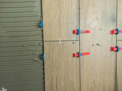 Laying tile on the floor, ceramic tile laying, pressing down and regulating,  Stock Photos