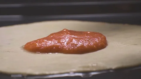 Laying tomato paste on the dough for pizza. Video Stock Footage 85102754