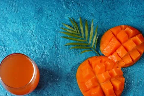 The layout on a bright blue background. Mango, a glass of juice and a palm le Stock Photos