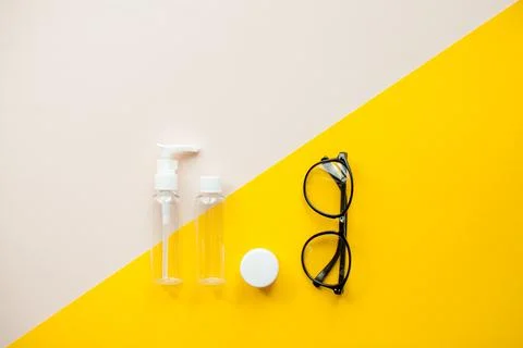 Layout on a bright yellow background. Cosmetics jars and glasses. Travel set Stock Photos