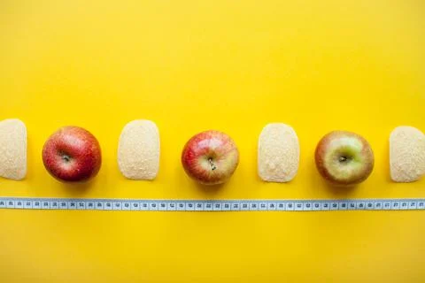A layout of chips and apples and a measuring tape on a bright yellow background Stock Photos