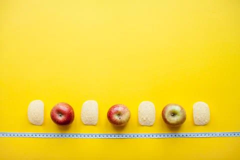 A layout of chips and apples and a measuring tape on a bright yellow background Stock Photos