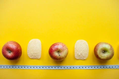 A layout of chips and apples and a measuring tape on a bright yellow background Stock Photos