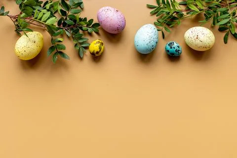 Layout of colorful Easter eggs with spring branches and green leaves, top view Stock Photos