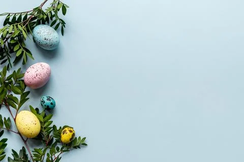 Layout of colorful Easter eggs with spring branches and green leaves, top view 스톡 사진