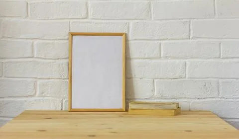 The layout of an empty photo frame and old books on a wooden table . Stock Photos