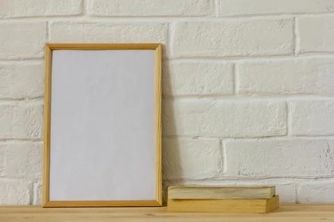 The layout of an empty photo frame and old books on a wooden table . Stock Photos