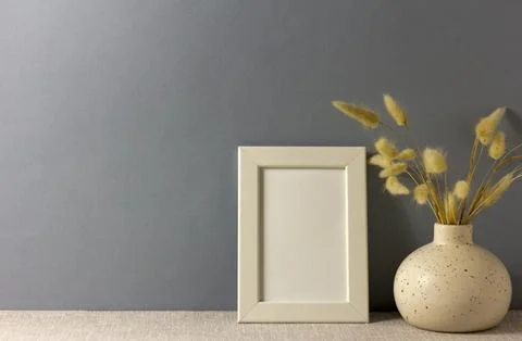 The layout of an empty photo frame on the table. A vase with dry grass. A m.. Stock Photos