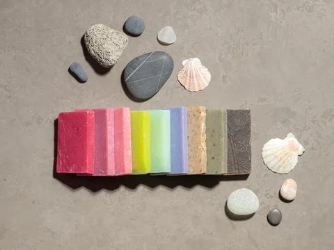 A layout of pieces of colored soap, shells and sea pebbles on a gray background Stock Photos