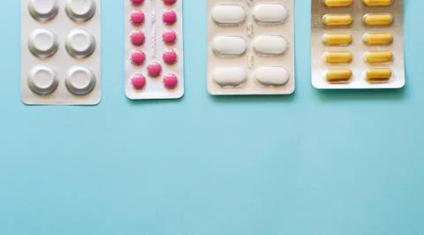 Layout of tablets and capsules on a plain blue background Stock Photos