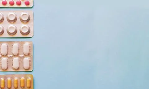 Layout of tablets and capsules on a plain blue background Stock Photos