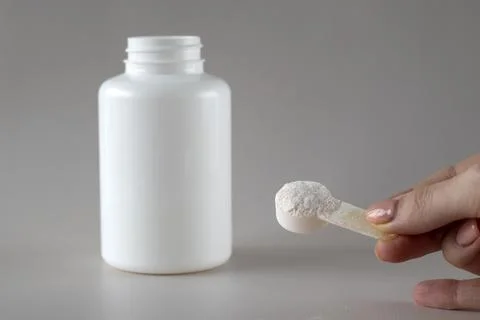 Layout of a white bottle of supplements and a spoonful of electrolyte powder and Stock Photos