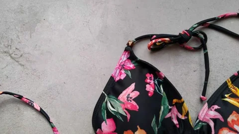 The layout of a women's bikini, a black swimsuit with a floral pattern on a gray Video stock 166166015