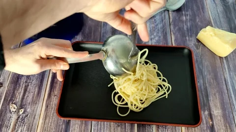 Lays out boiled spaghetti in the form of a nest on a black plate Stock Footage 227721979