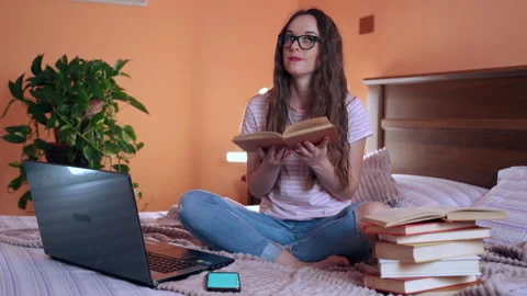 Lazy bones concept, student studying at home,choice between books and smartphone Stock Footage 134405411