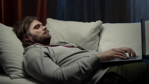 Lazy man freelancer working with laptop lying on the couch. Lazy worker typing Video stock 249026328