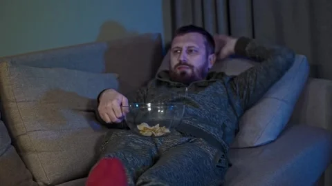 Lazy Man Lying on the Couch in a Dark Room, Mindlessly Watching TV, Eating Chips 스톡 동영상 300311345