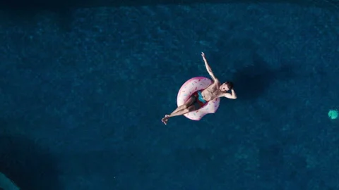 Lazy man swimming in inflatable ring in the pool, top aerial view. Stock Footage 269120668