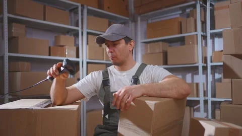 Lazy man in uniform loader procrastination ,scans boxes with barcode scanner Stock Footage 272909456