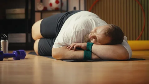 Lazy plus-size man napping on mat instead of working out, procrastination Stock Footage 310002858