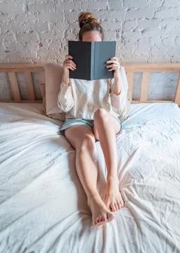 Lazy time in bed. Unrecognizable young woman relax at morning holding and Stock Photos