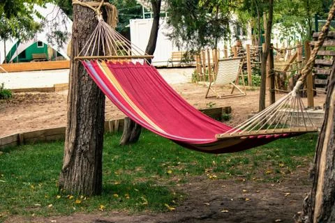 Lazy time. Empty red hammock connected to the tree. Stock Photos