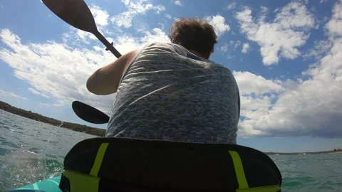 LD Low angle shot behind a man paddling a kayak at sea in sunshine Stock Footage 136050829