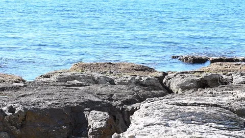 LD Sea waves gently flowing over the rocky Mediterranean coastline on a sunny da Stock Footage 125854531