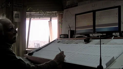 Lderly Train Dispatcher Working at Control Panel Desk with Monitors - 4K Stock Footage 337646576