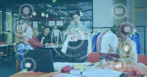 Lead designer wearing gray blazer presenting two garments in open-plan studio, Stock Photos